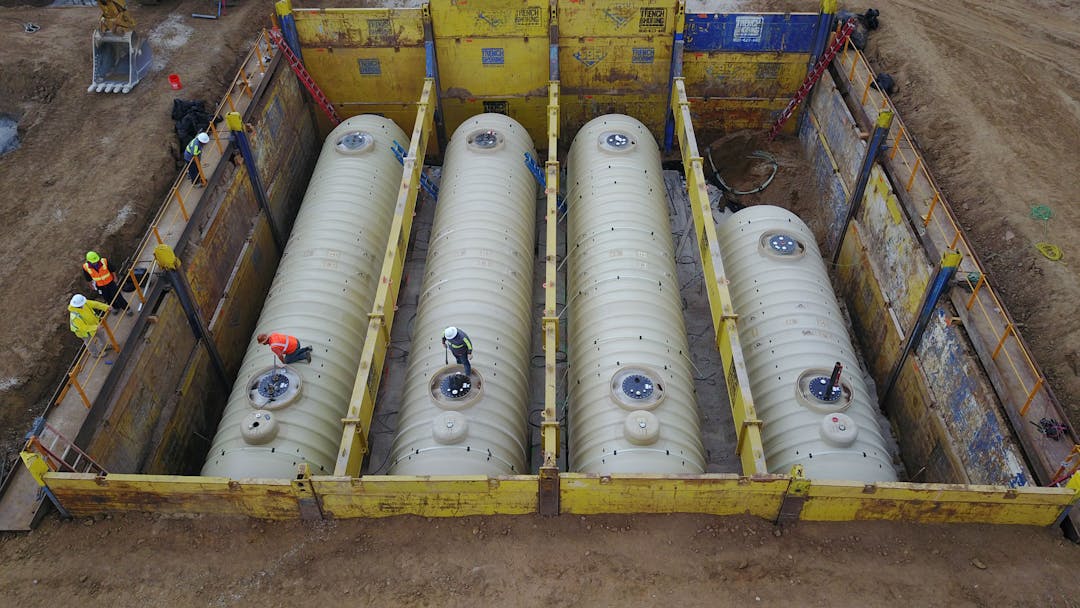 Underground installation of pipeline tanks, separated into 4 parts, with employees around and on the tanks