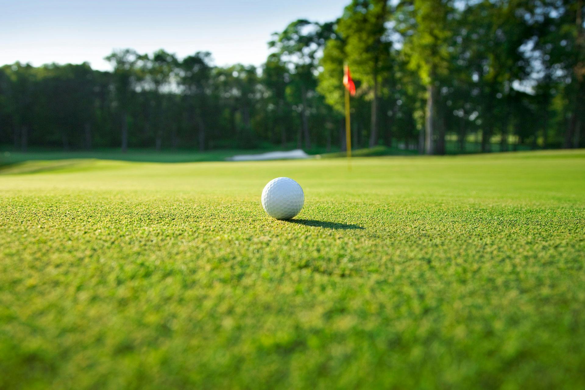 Golf ball on a grassy golf course with a flagstick in the distant background