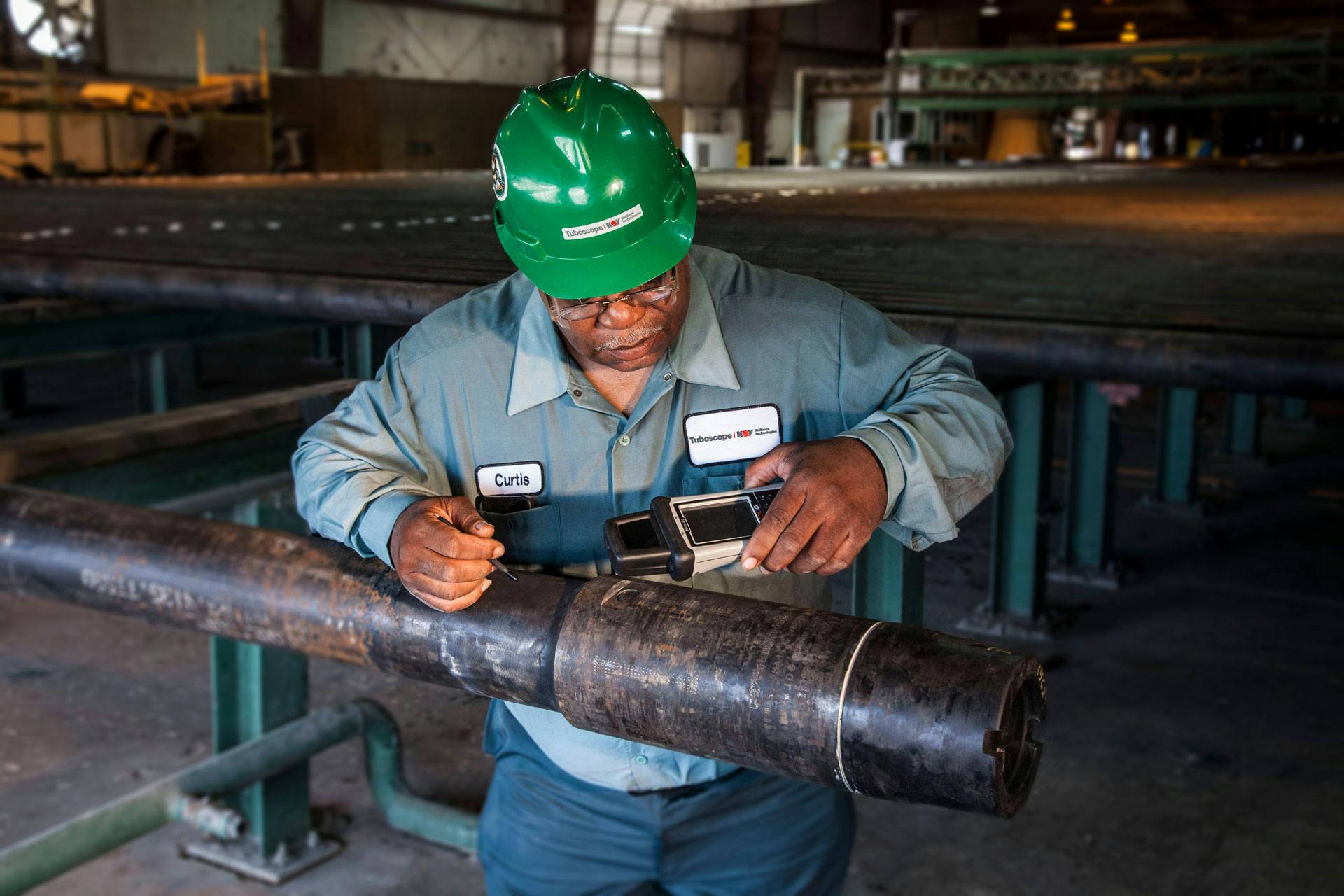 NOV Tuboscope employee checking drill pipe while in a facility