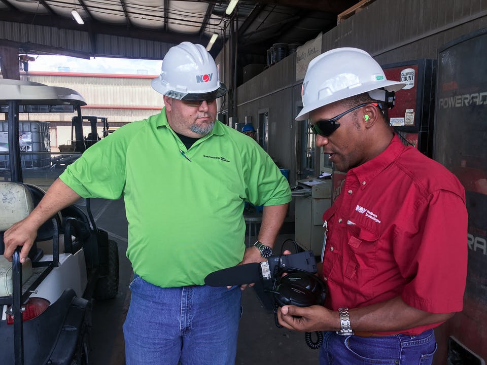 Michael Gaines interviewing an employee at the Grant Prideco facility in Navasota, TX, while standing next to a golf cart