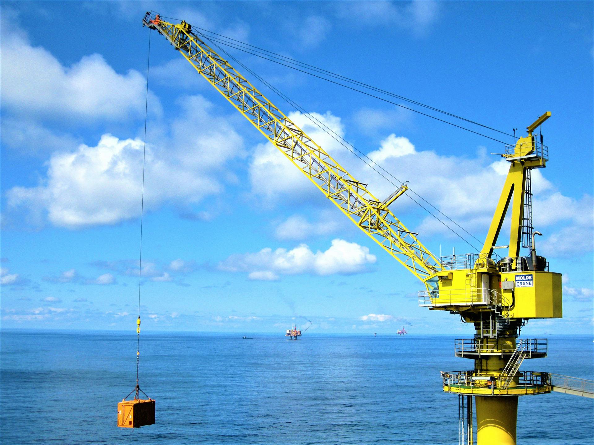 MoldeCrane lifting orange container, with clouds and the horizon in the background