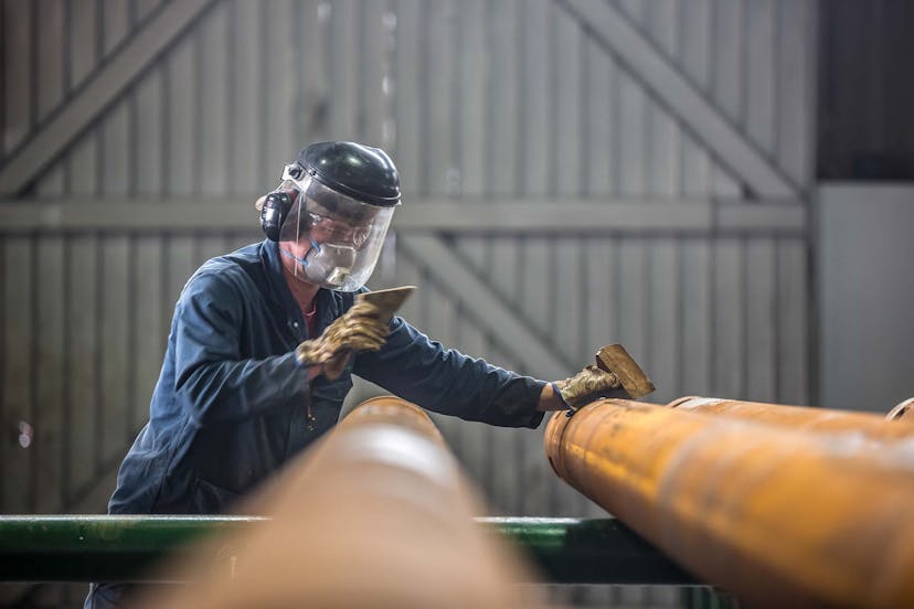 A technician inspects a pipe during manufacturing