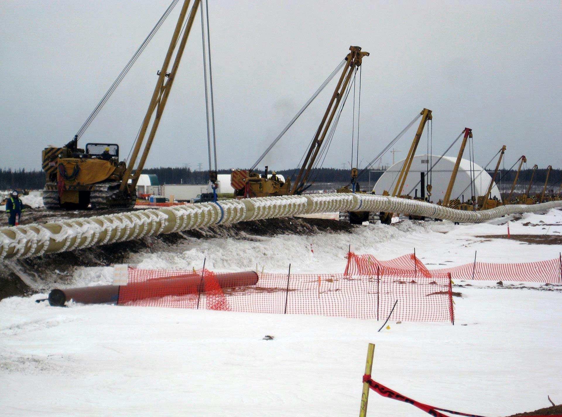 A line of Green Thread Fiberglass Pipe being laid in a snowy landscape