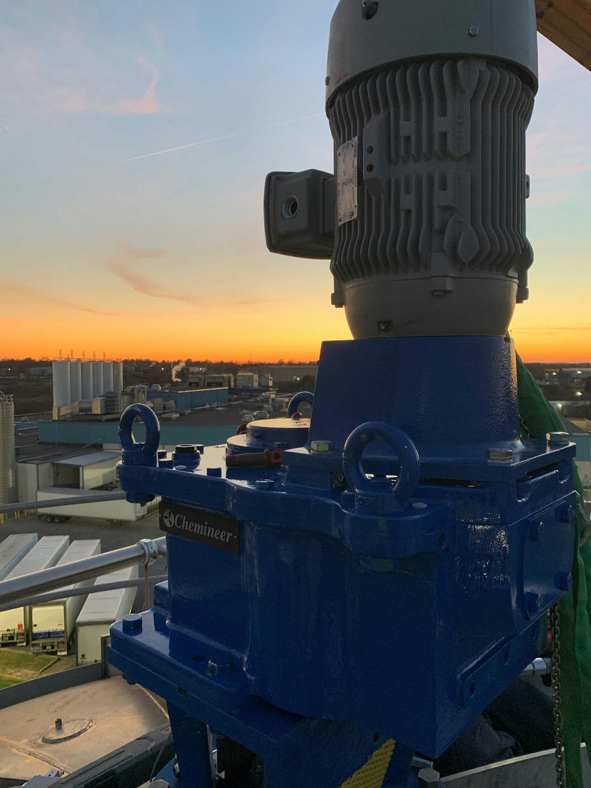 Upclose photo of a Chemineer mixer outside of a cacility, with a sunset in the background
