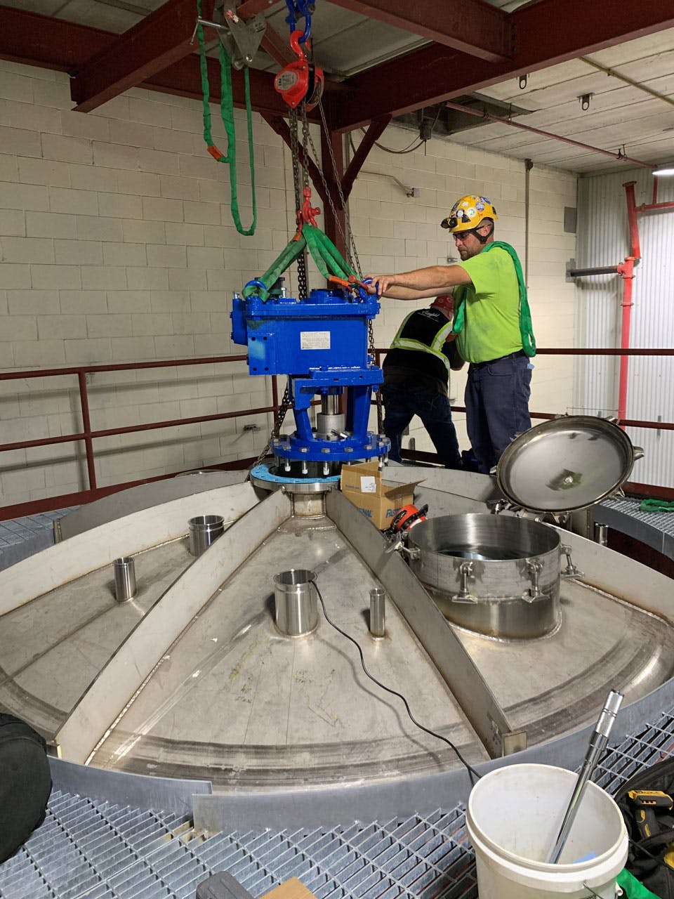 NOV employees working on a mixer and open container in a facility