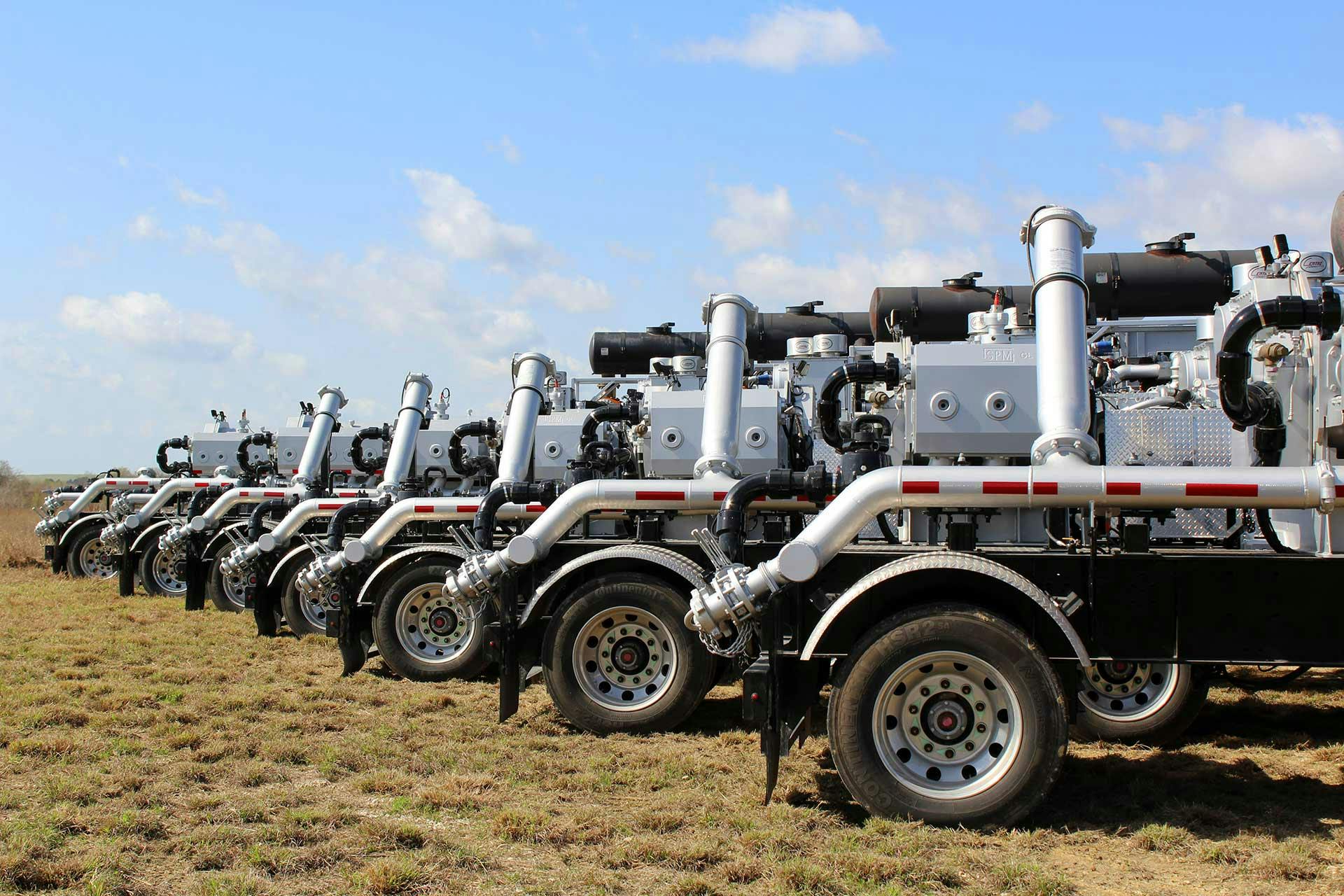 A row of Trailer-Mounted Frac Pumpers in field