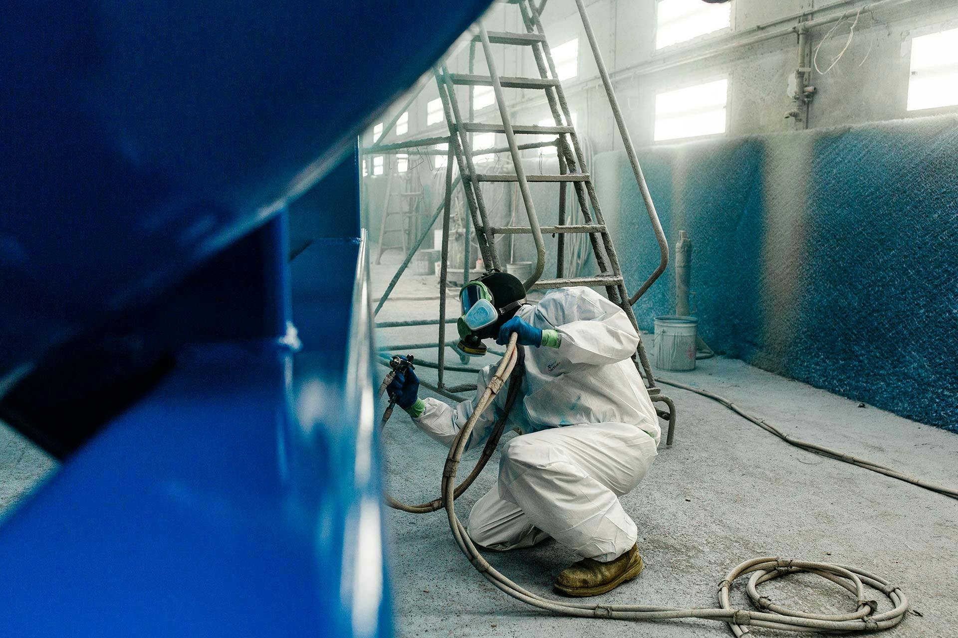 Image of an employee spray painting a piece of equipment
