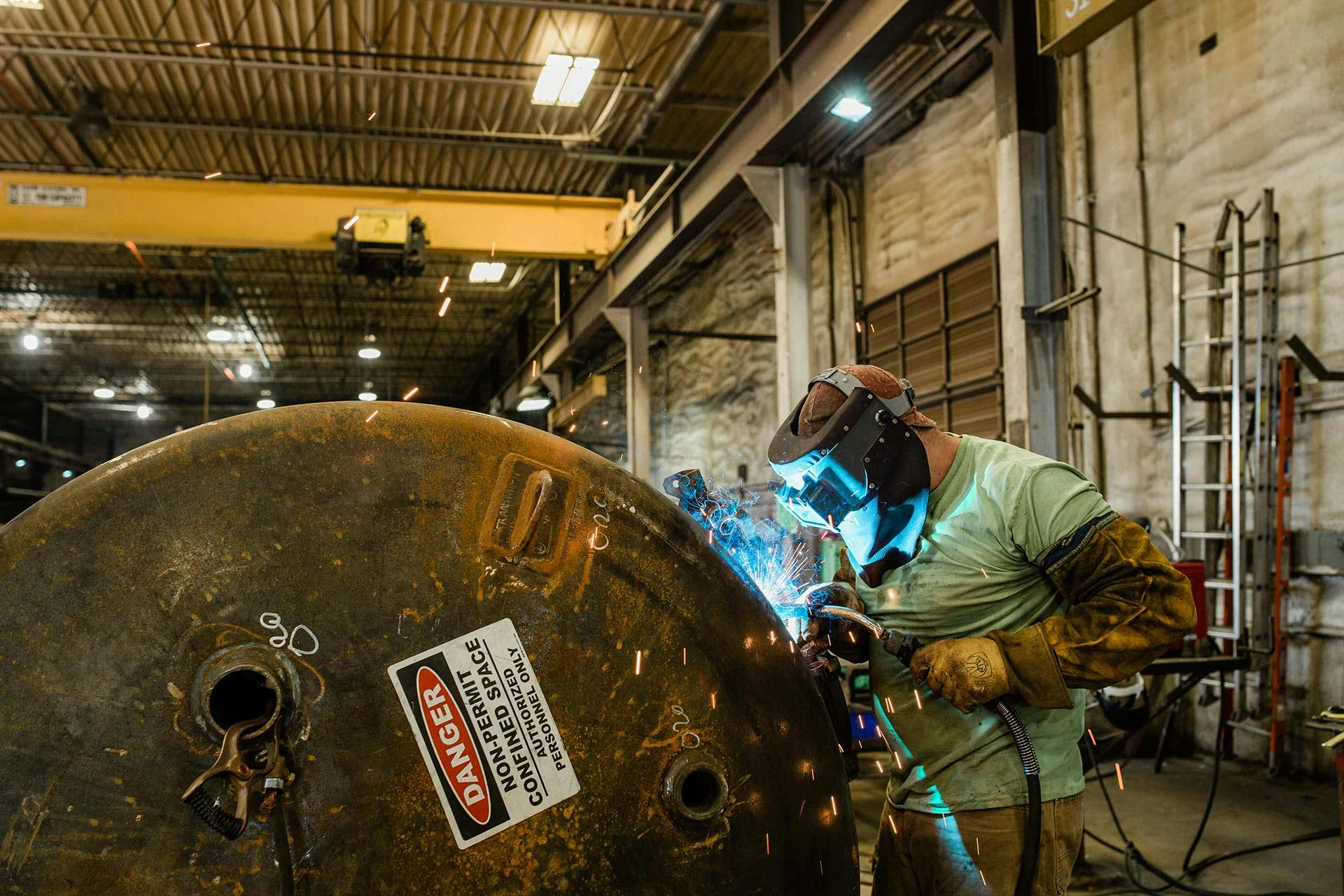 Image of a man welding a piece of equipment from the side