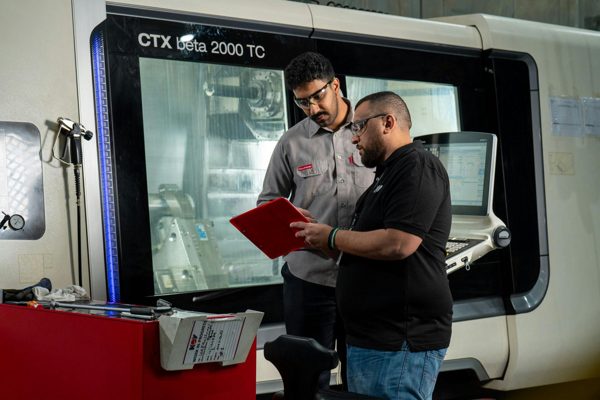 Two NOV employees reviewing information in front of a CTX beta 2000 TC, at the Dammam Chokes Manufacturing Plant