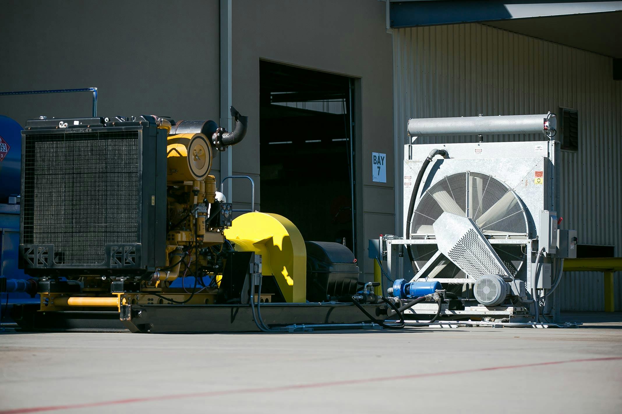 Back of a DuraTester Drilling Motor Test Stand in front of a warehouse and large fan