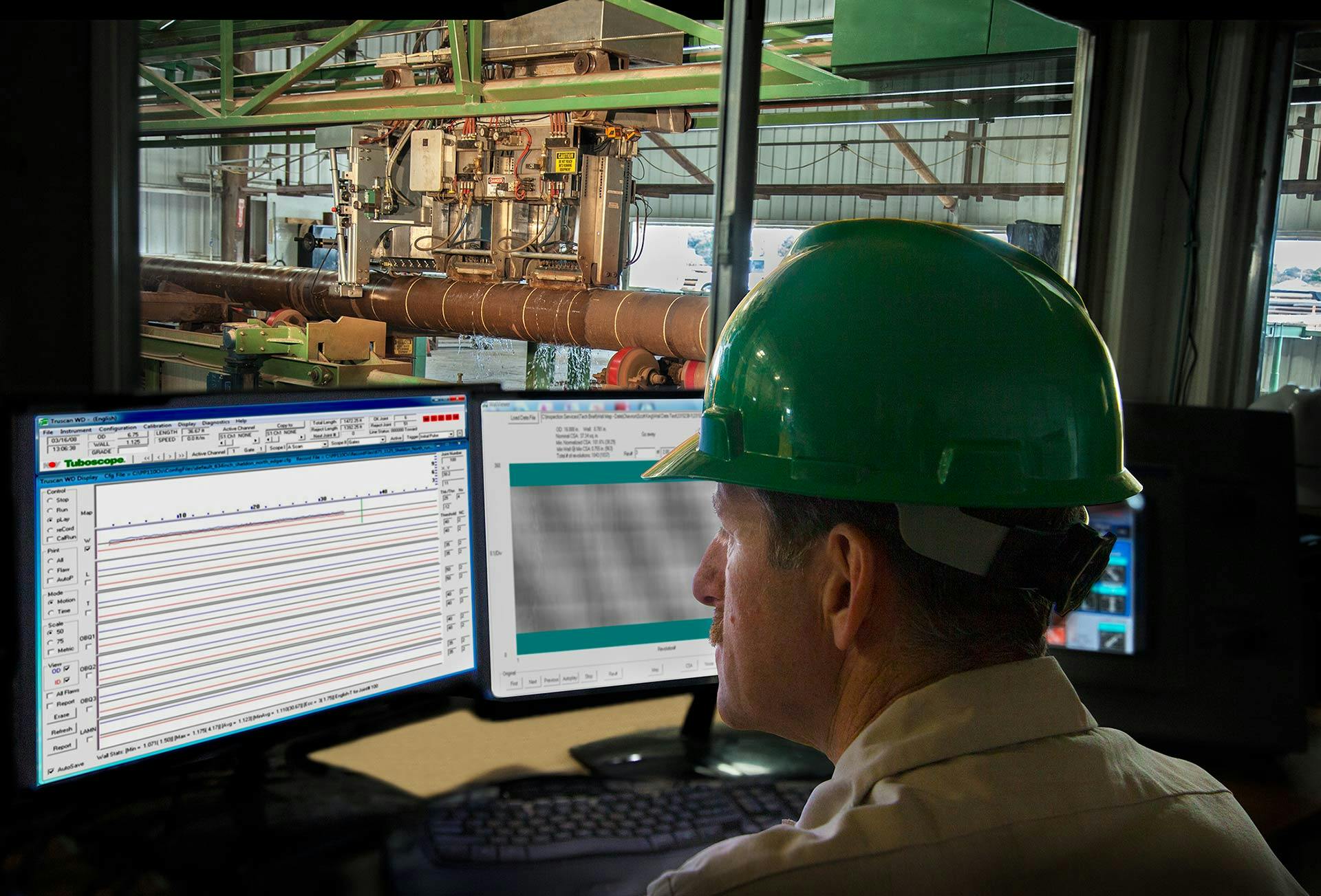 Image of an engineer viewing screens with shop in the background.