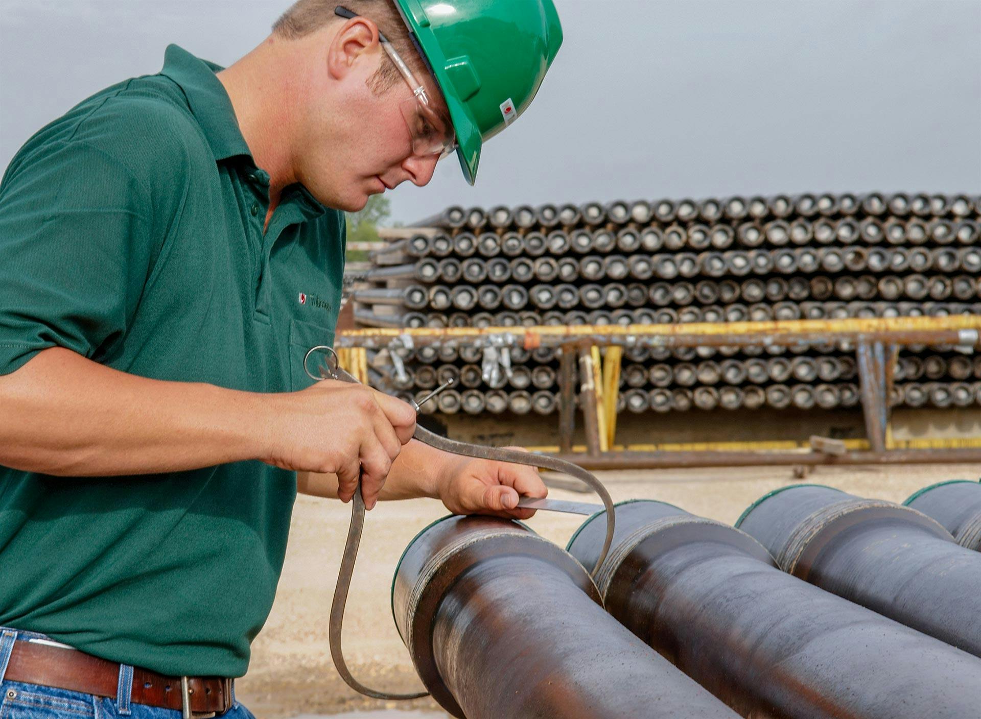 Worker performing inspection of the male ends of drill pipe