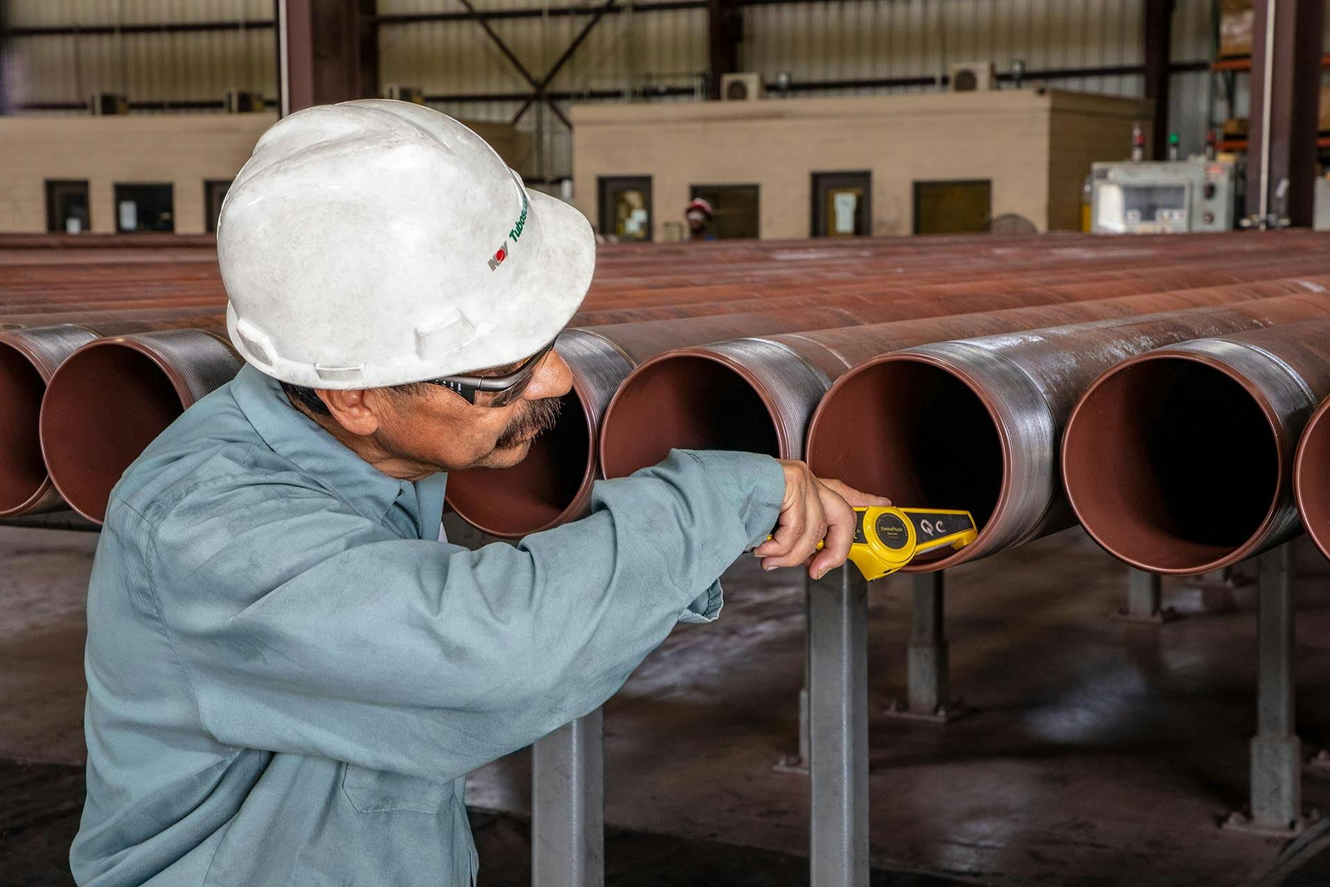 Tuboscope worker inspecting internal TK coatings on drill pipe for QC