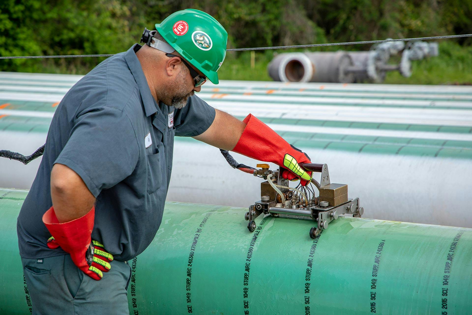 Image of an NOV employee using Tuboscope equipment to inspect line pipe.