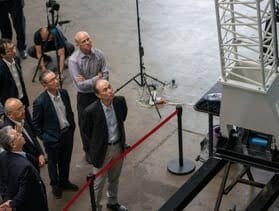 Men looking up at a tall white lattice model.
