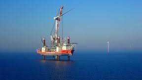Offshore jack-up vessel with crane installing a wind turbine among others in the sea.