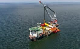 Pipe-laying vessel with a large crane offshore.