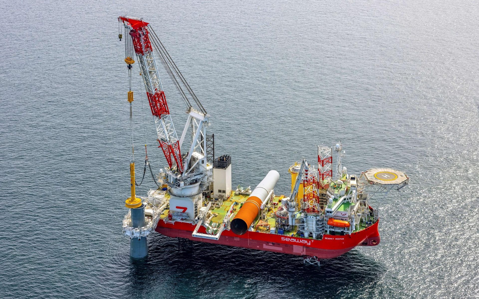 Aerial shot: Red crane vessel Seaway Ventus installs a large offshore foundation pile.