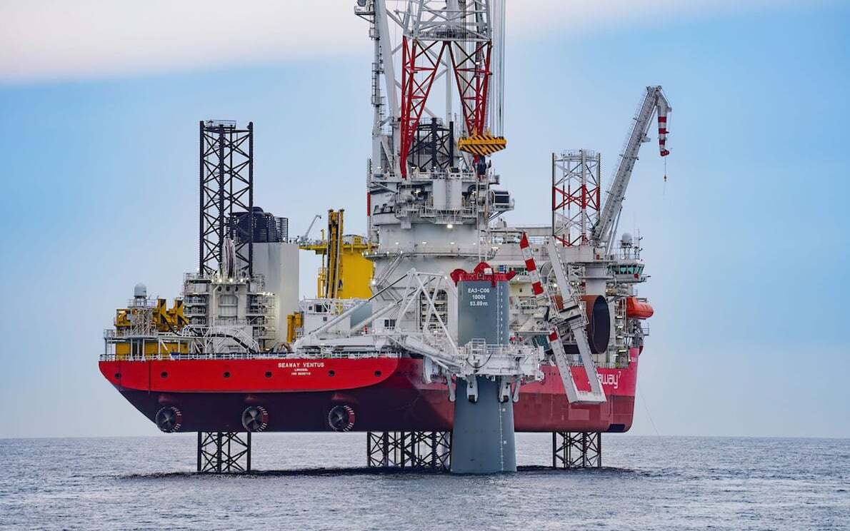A massive red and white offshore wind turbine installation vessel, the Seaway Ventus, on the open sea.